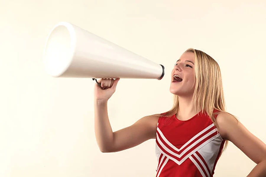 Female cheerleader holding plain white plastic megaphone