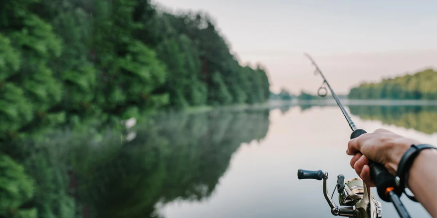 Fisherman with rod, spinning reel on the river bank