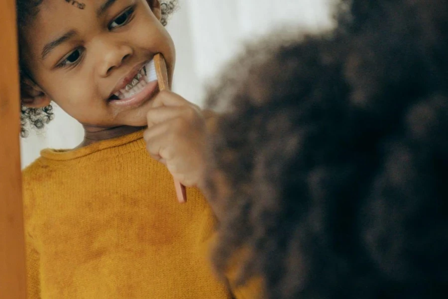 Focused African American kid cleaning teeth looking at mirror