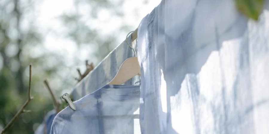 From below of washed clothes hanging on clothesline in green yard on sunny day