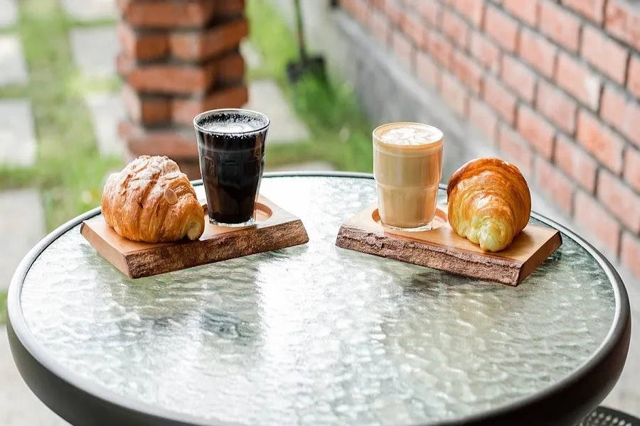 Glass coffee table with croissants and coffee served