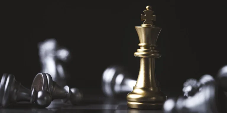 Golden king chess standing among fallen silver chess for winner and defeat after competition