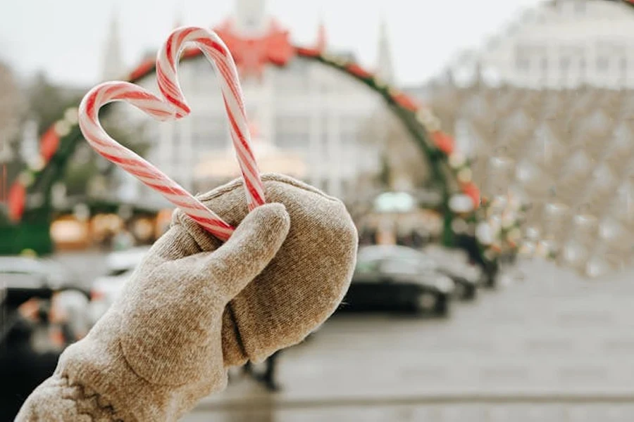 Hand in a snug mitten holding a heart-shaped candy