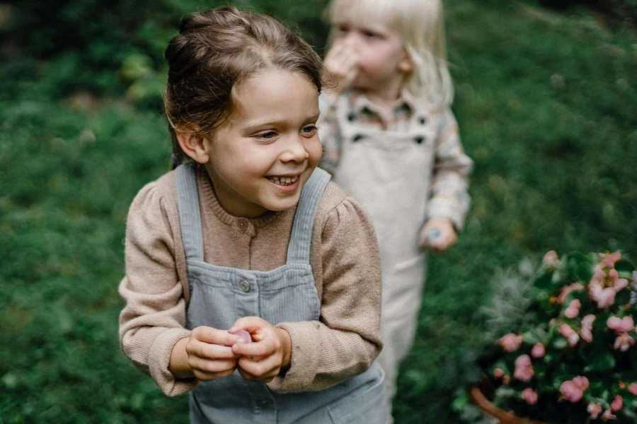 Happy little siblings standing in lush garden