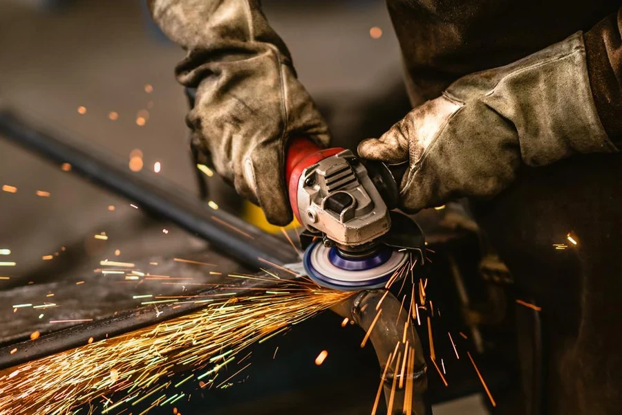 Heavy industry worker grinds steel with an angle grinder,sparks flying,close up.