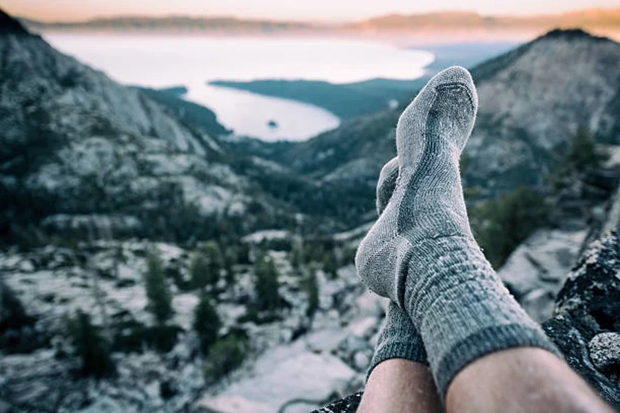 Hiker wearing socks without boots at top of mountain