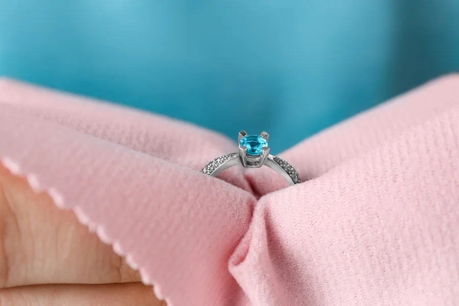 Jeweler cleaning topaz ring with microfiber cloth, closeup