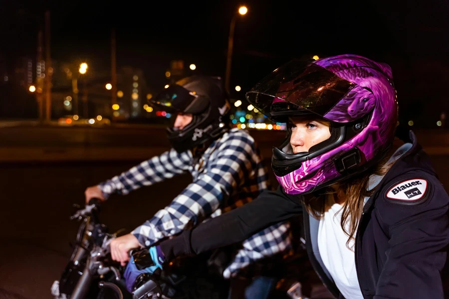 Man and Woman Wearing Helmets and Riding on Motorbikes at Night