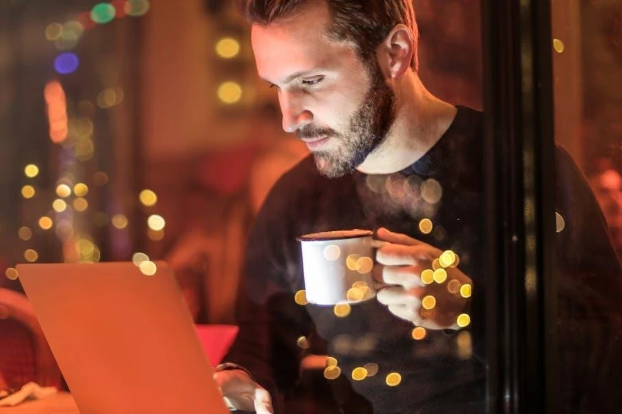 Man holding mug in front of laptop