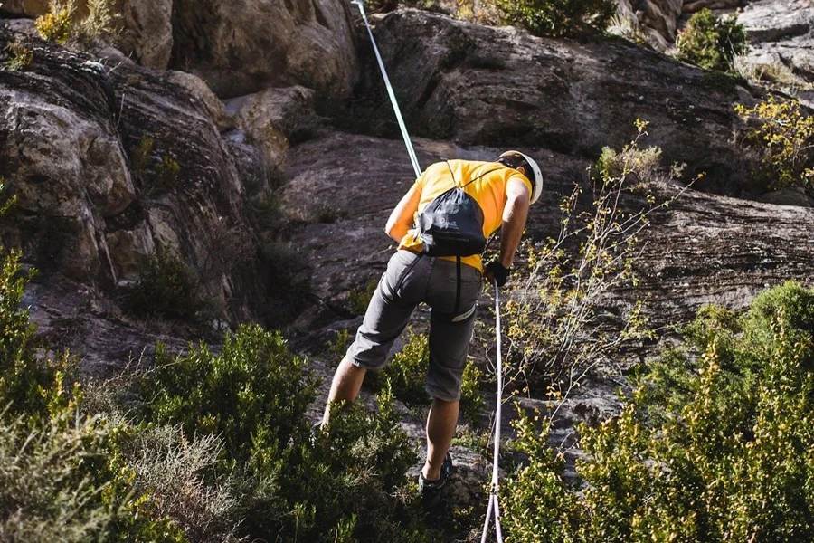 Man in climbing harness rappelling on a rock