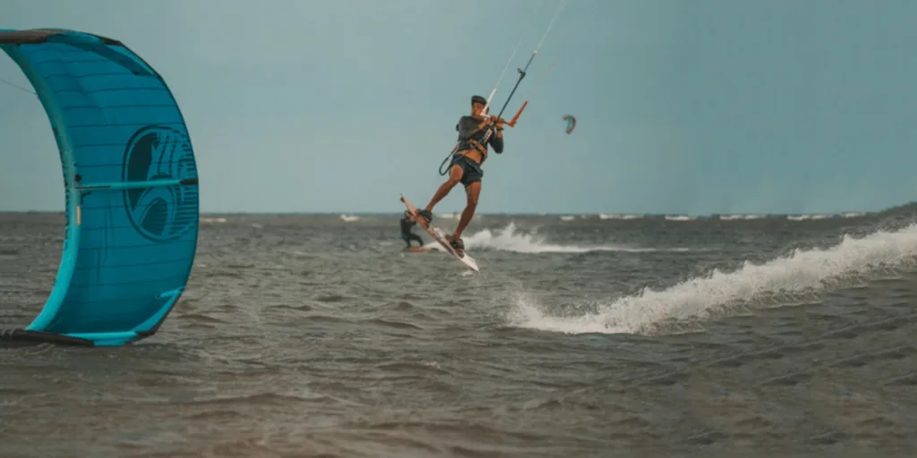 Man jumping in air while hanging onto kitesurfing board