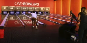 Man lining up bowling ball in bowling alley