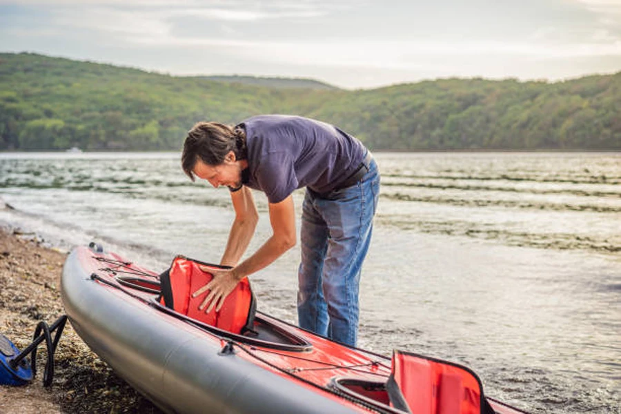 Man placing red dry bag backpack inside kayak