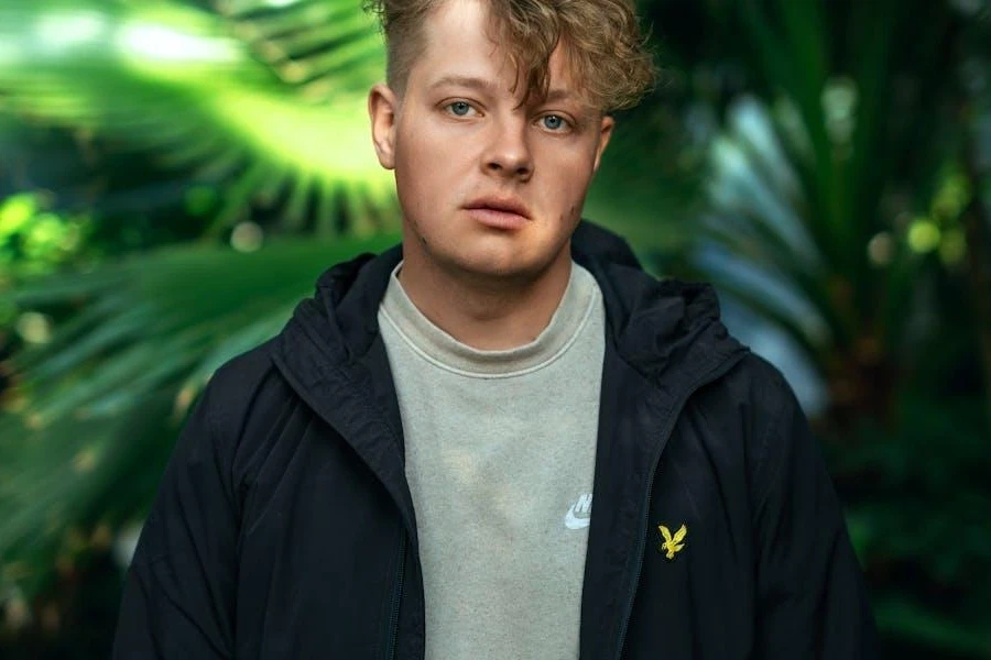 Man posing in black hooded windbreaker jacket