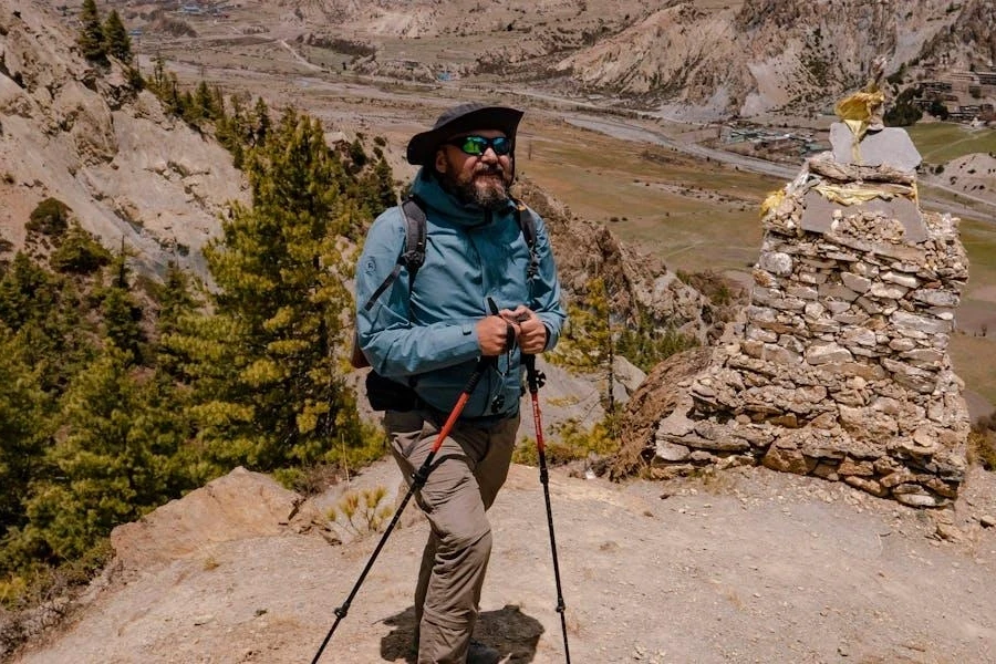 Man posing on a hill with walking sticks