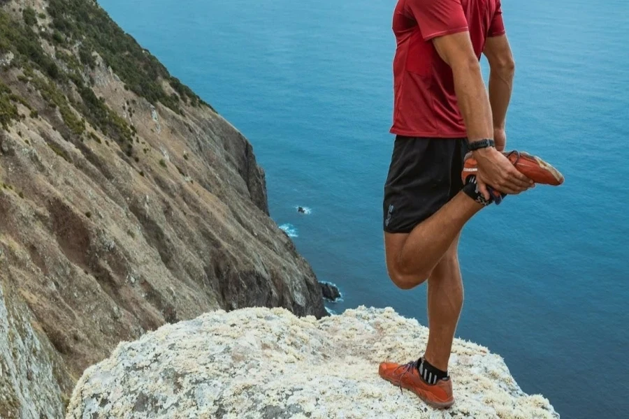 Man stretching in red trail running shoes