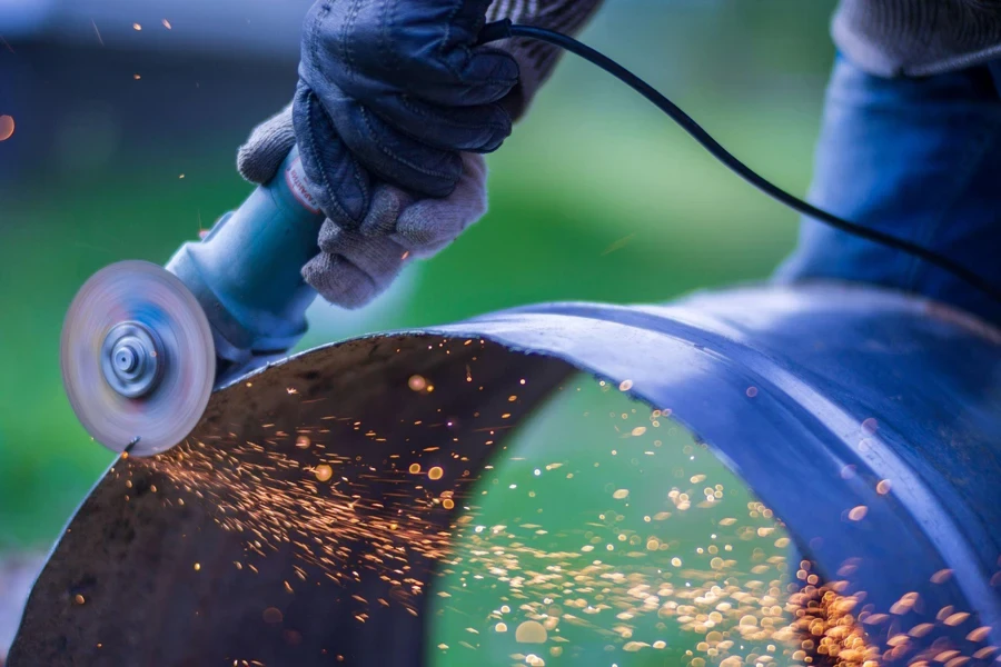 Man working with grinder saw, close up view on tool. Electric saw and hands of worker with sparks.