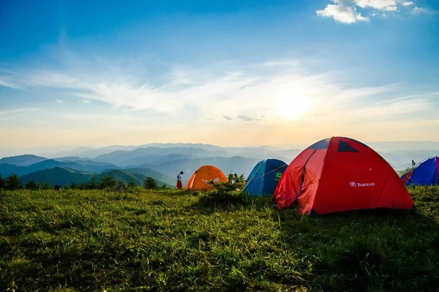 Multiple camping tents at a campsite overlooking mountain ranges