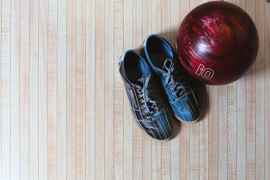 Pair of bowling shoes next to red bowling ball