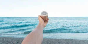Person Holding Upward Brown Speaker in Front of Sea