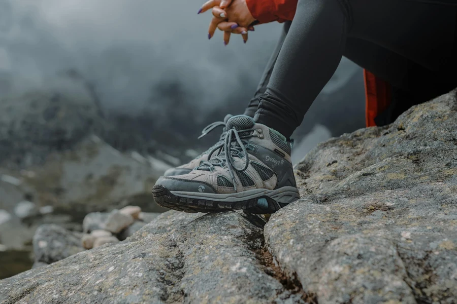Person Wearing Hiking Shoes Sitting on a Rock