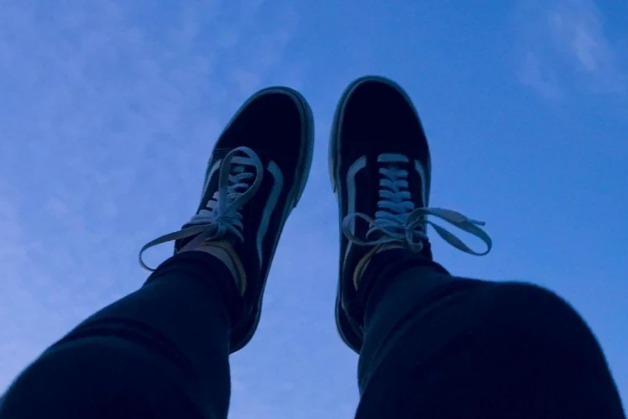 Person Wearing Sneakers Raising His Feet Pointing to The Sky