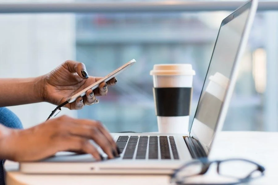 Person connecting phone to a laptop on a table