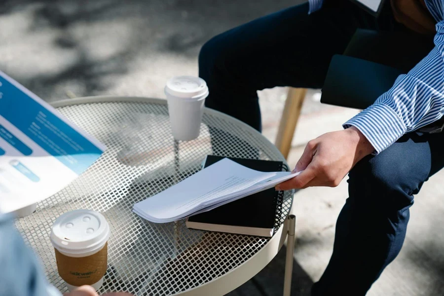 Person holding Papers on Top of a Table