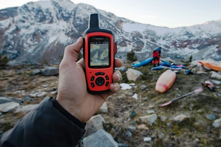 Person using a red handheld GPS unit at a campsite