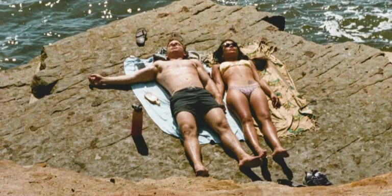Photo of Couple Lying Down on Cliff Near Sea