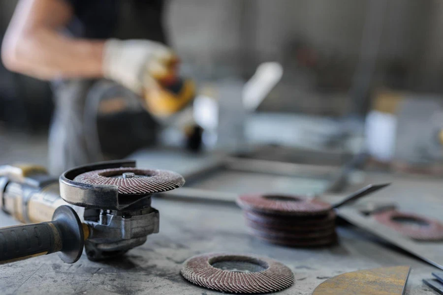 Polishing metal with a manual grinding machine with a polishing disc is on the table in the workshop.