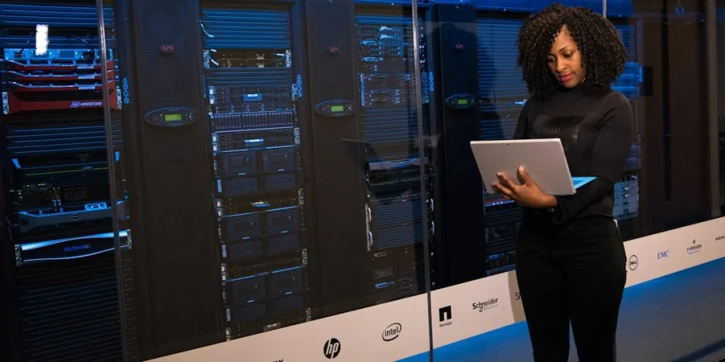 Software engineer standing beside server racks