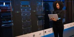 Software engineer standing beside server racks