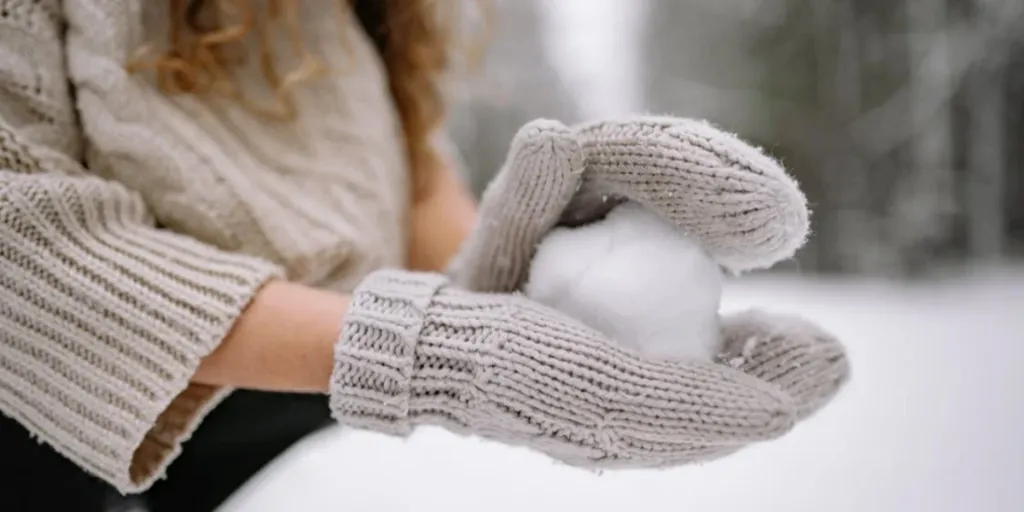 Thick beige knitted winter mittens with thumbs and cuffs