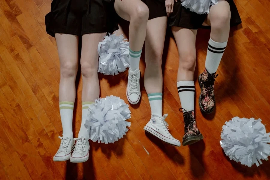 Three cheerleaders lying on the floor with white pom poms