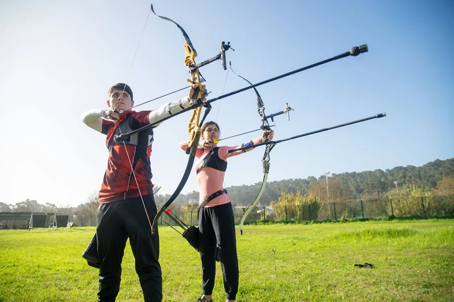 Two archers using hinge release aids to shoot