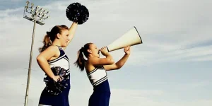 Two cheerleaders with pom poms and a megaphone