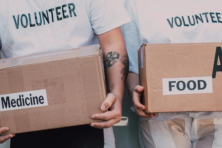 Two people holding boxes of medicine and food aid