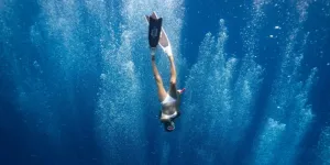 Unrecognizable Lady Swimming Underwater after Jumping in Ocean