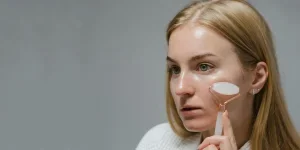 Mujer haciendo masaje facial con un rodillo de jade blanco