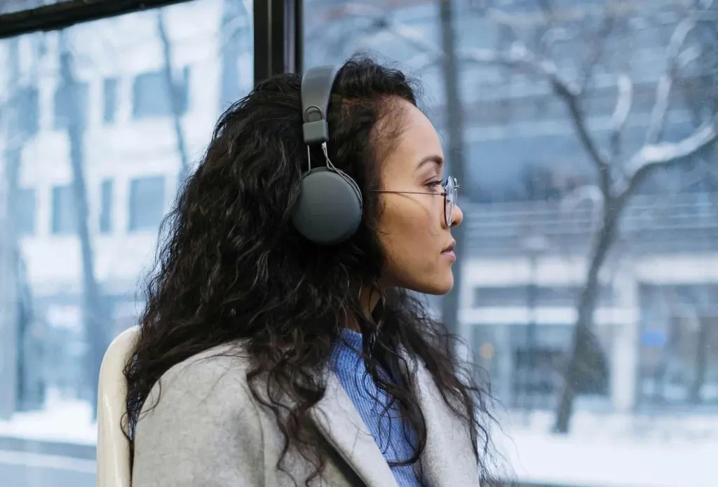 Woman Wearing Headphones and Holding a Smartphone Sitting in a Bus