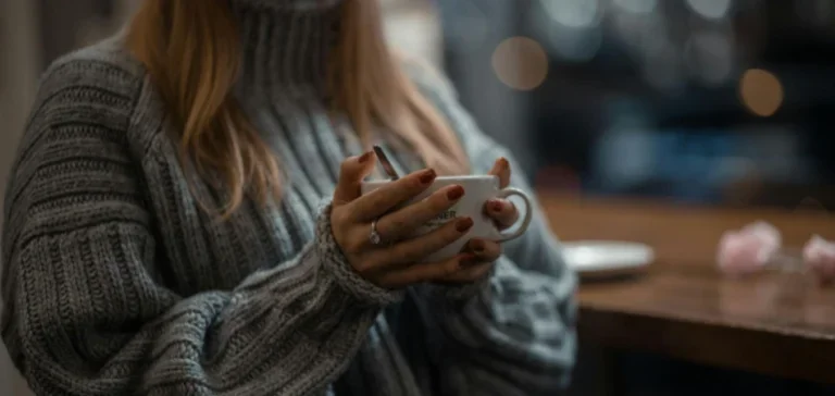 Mujer En Suéter De Punto Gris Sosteniendo Taza De Cerámica Blanca