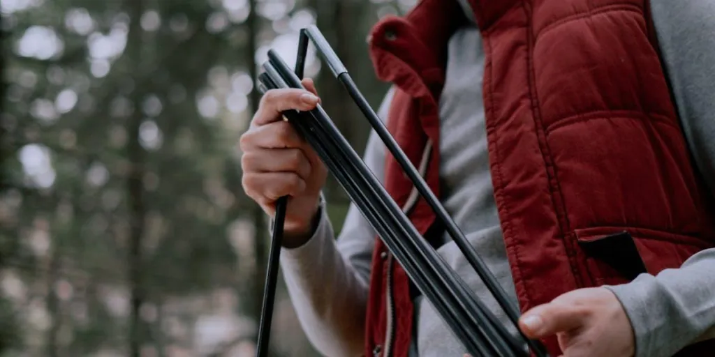 Woman in a red jacket assembling tent poles