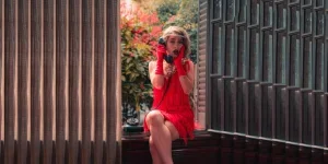 Mujer con un vestido flapper rojo con borlas y guantes a juego