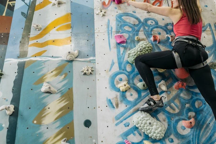 Woman in climbing harness ascending with wall grips