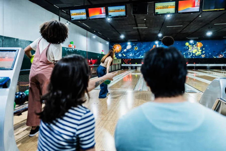 Woman launching ball down bowling alley with friends