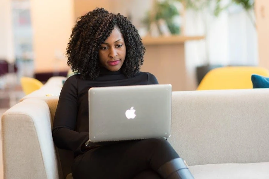 Woman using a MacBook Pro on a white couch