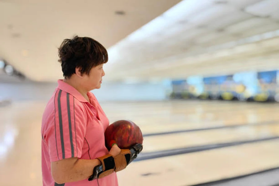 Woman wearing bowling gloves while holding bowling ball