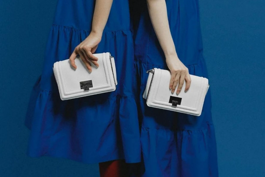 Women in Blue Dresses and White Bags Standing Back to Back