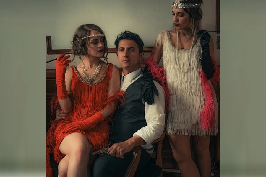 Women in flapper dresses around a man in 1920s fashion